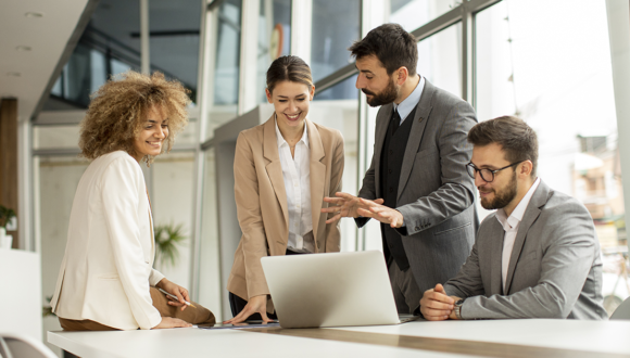 Four people gather around a computer