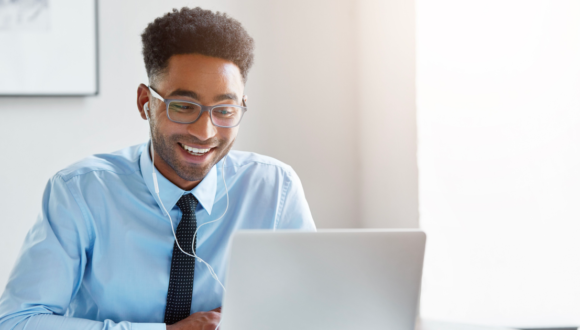 Person wearing earphones smiles at computer screen